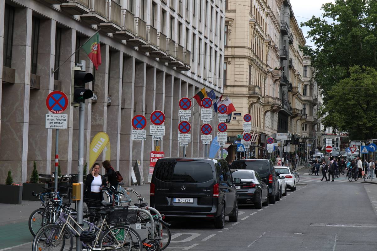 A dozen parking restriction signs litter a sidewalk