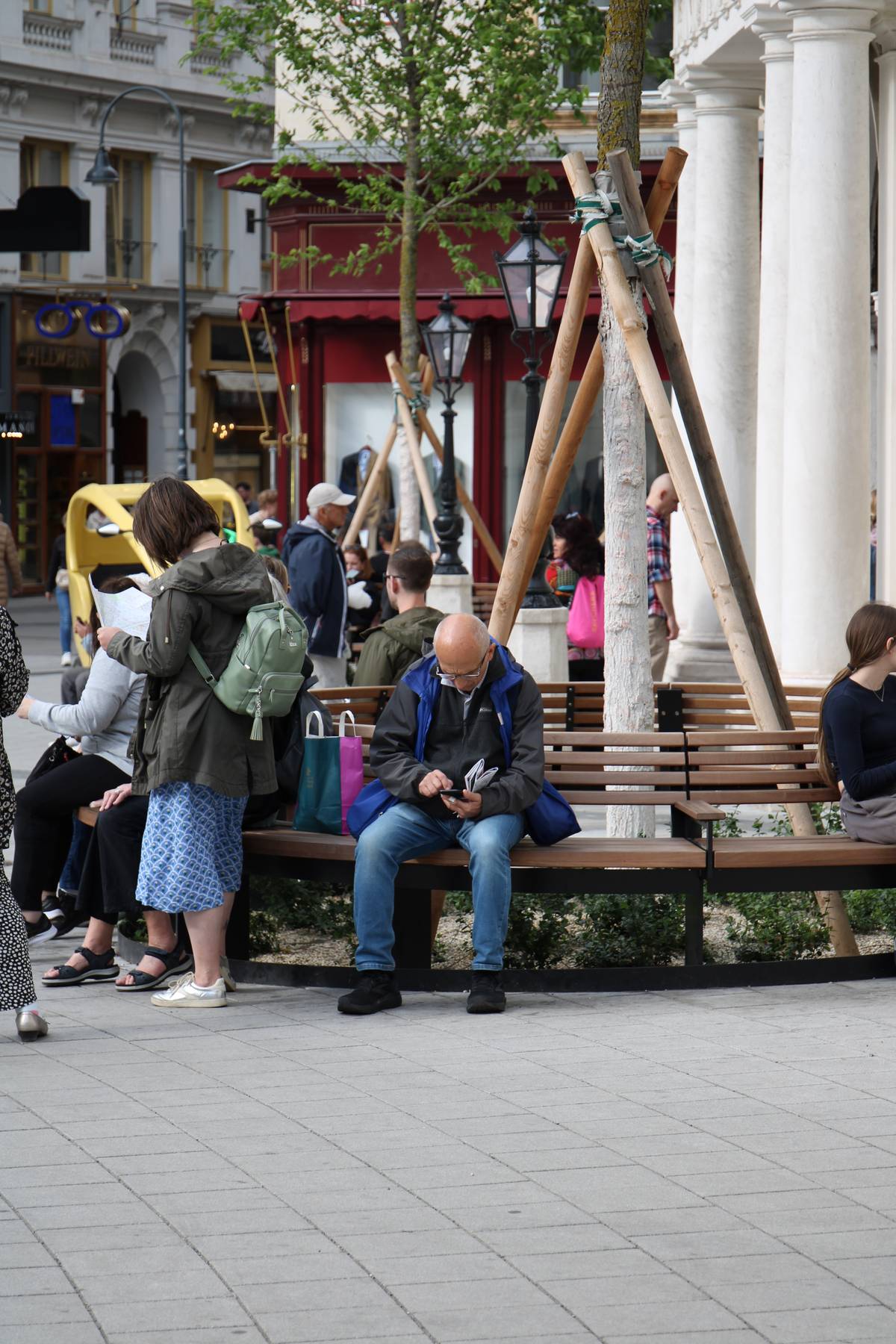 My father sits at a bench and looks at his phone