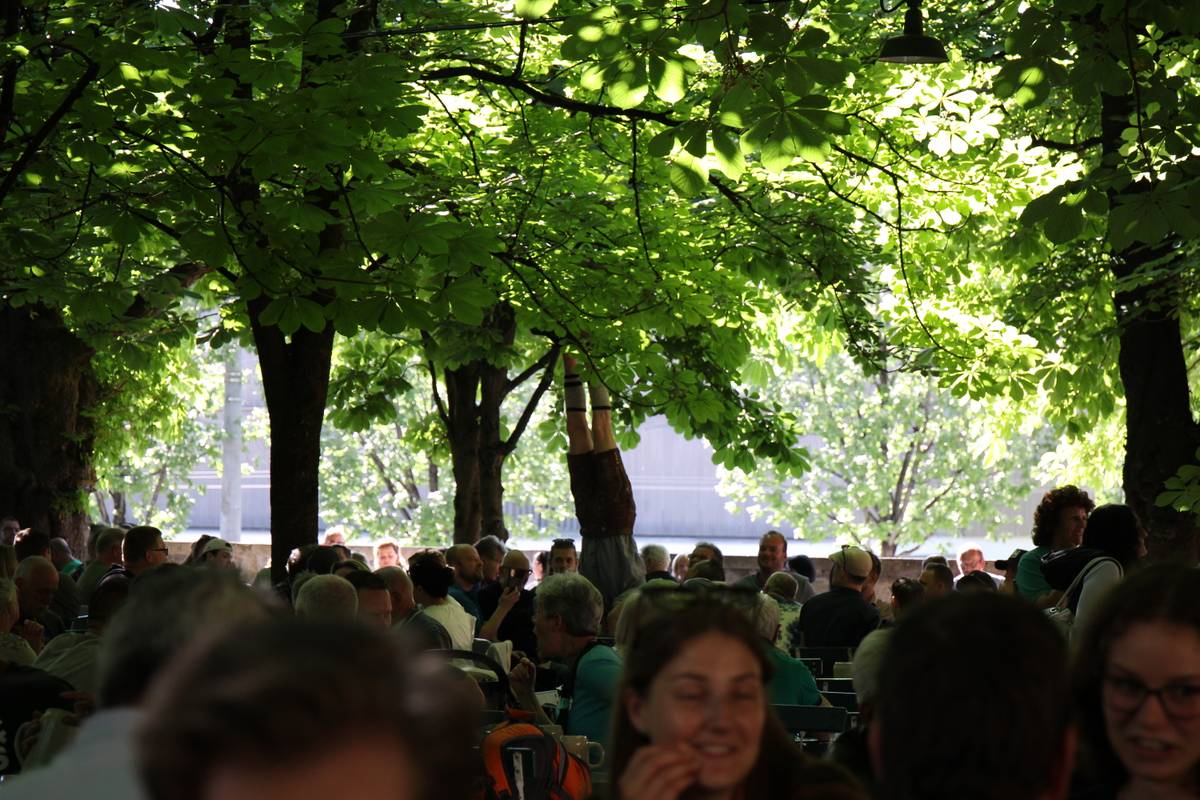 A guy does a handstand on top of a table in a beer garden