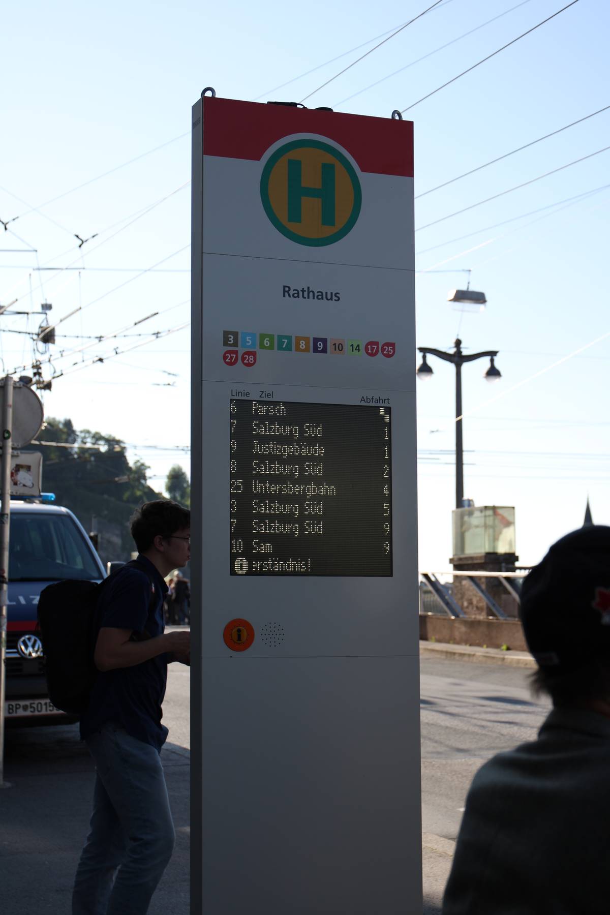 A bus stop has a sign with digital arrival estimates.
