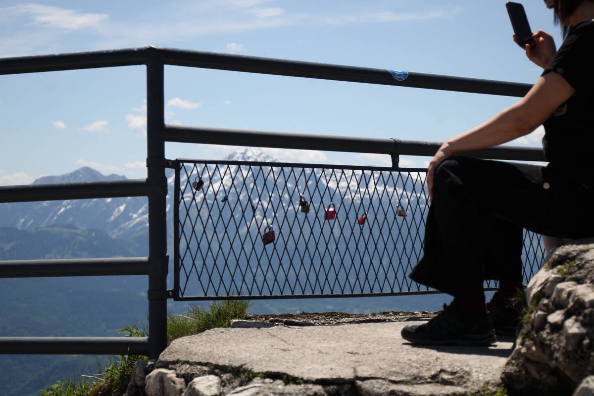 Locks are attached to a chain fence. Out of focus and behind the fence is the mountain range.