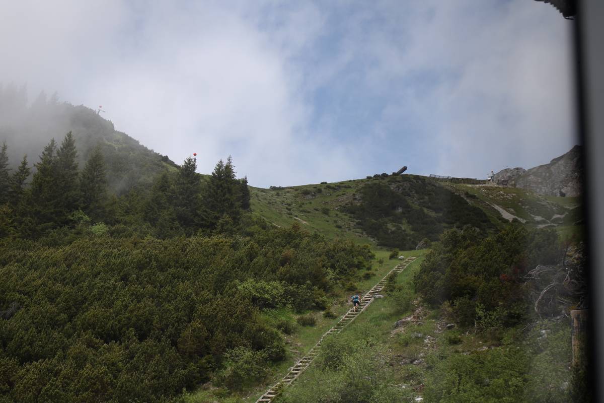 A man climbs up a wooden staircase embedded in the hill