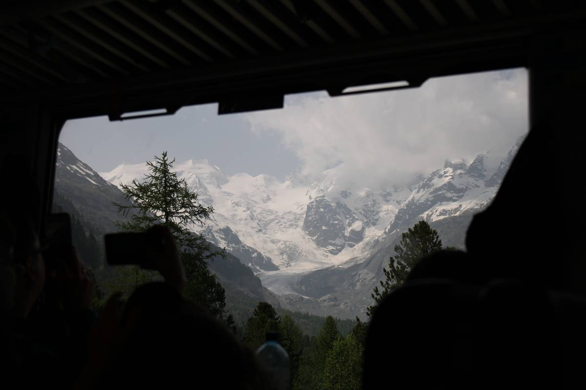 A view out the window of the train. White capped mountains are visible.