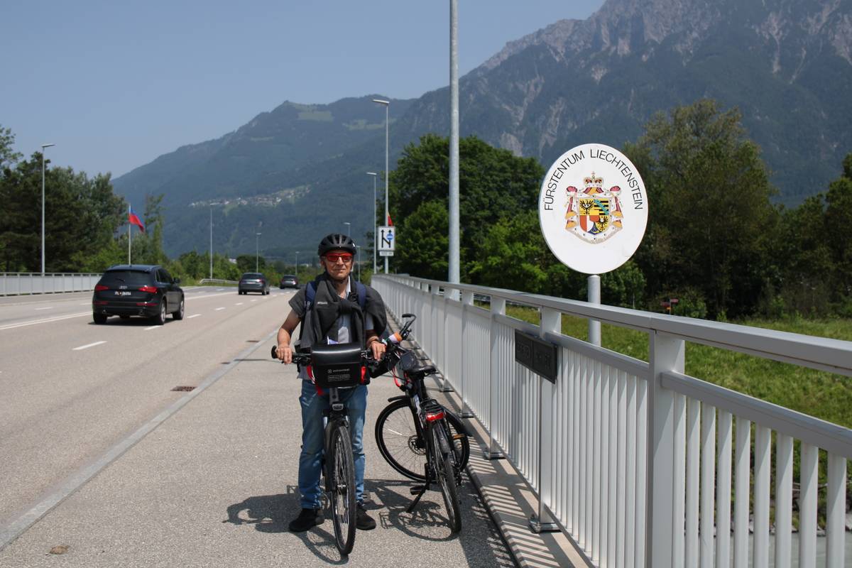 My dad stands with his bike next to the sign that says you are entering Lichtenstein