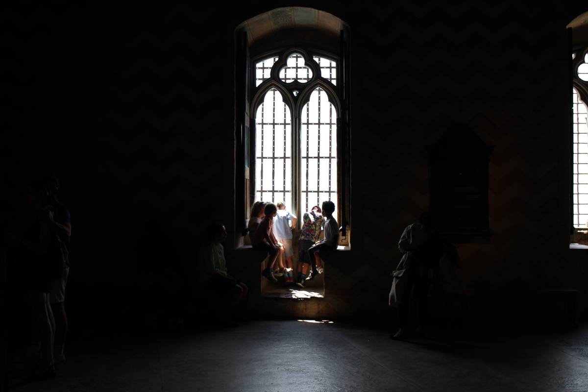 Some kids sit in the window of a room in the castle